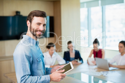 Portrait of smiling female business executive standing in conference room with digital tablet