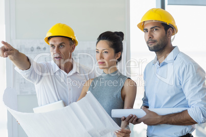 Three architects discussing over blueprint