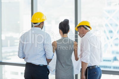 Three architects discussing over blueprint in office
