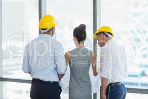 Three architects discussing over blueprint in office