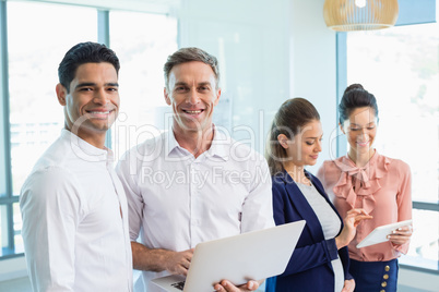 Portrait of confident architects holding laptop and digital tablet