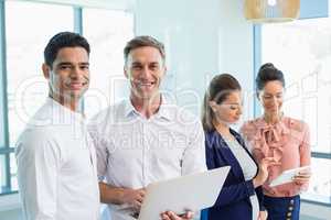 Portrait of confident architects holding laptop and digital tablet