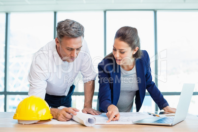 Two architects discussing over blueprint