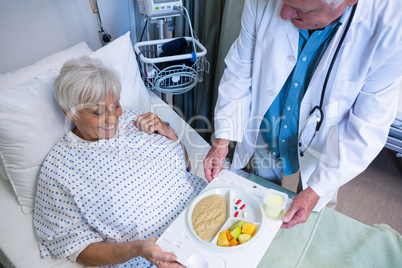Doctor serving breakfast and medicine to senior patient