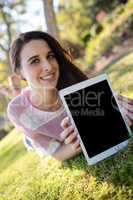 Woman lying on grass and holding digital tablet