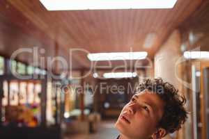 Thoughtful schoolboy looking up in corridor