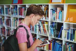 Attentive schoolboy using digital tablet in library
