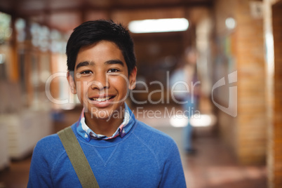 Portrait of smiling schoolboy standing in corridor