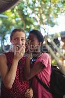 Schoolgirl whispering in her friends ear
