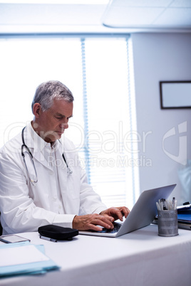 Doctor sitting at table and using laptop
