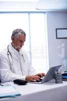 Doctor sitting at table and using laptop