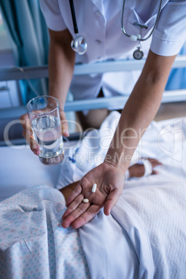 Female doctor giving medicine to patient in hospital