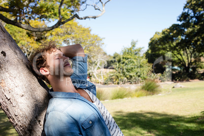 Man relaxing on tree trunk in park