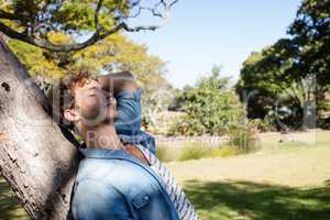 Man relaxing on tree trunk in park