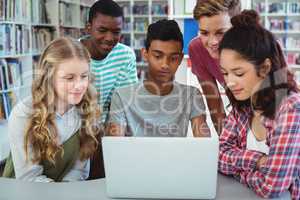 Attentive classmates using laptop in library