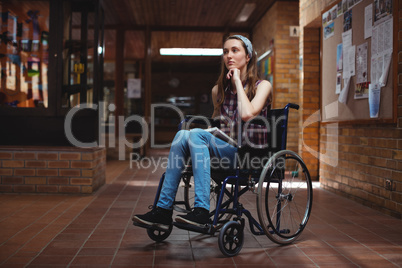 Disabled schoolgirl on wheelchair in corridor at school