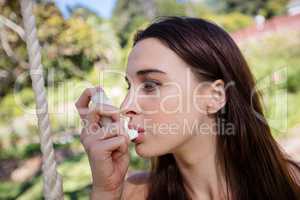 Woman sitting on swing using an asthma inhaler