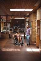 Schoolgirl talking with her disabled friend in corridor
