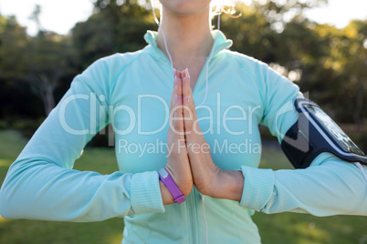 Mid section of female jogger listening to music and exercising with hands joint