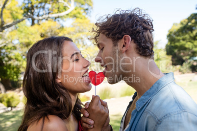 Romantic couple licking a heart shaped lollypop