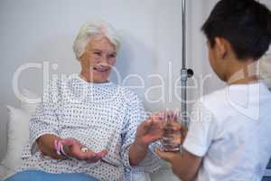 Boy giving a glass of water to senior patient