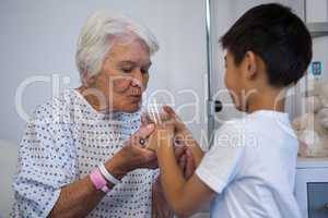 Boy giving a glass of water to senior patient