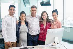 Portrait of business colleagues standing together at desk in office