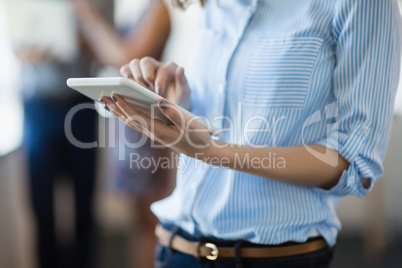 Mid section of business executive using digital tablet