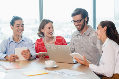 Smiling business executives discussing with each other in conference room