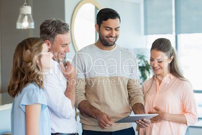 Business executives discussing over digital tablet in office Business executives discussing over digital tablet in office