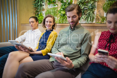 Business executives using electronic devices while sitting