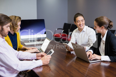 Business executives using electronic devices on conference table