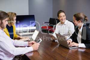 Business executives using electronic devices on conference table