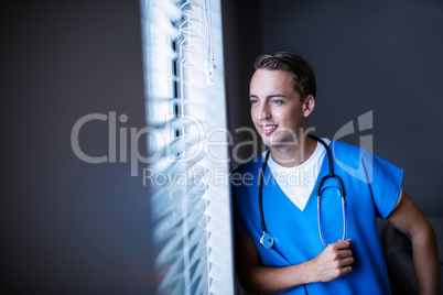 Thoughtful doctor looking through window