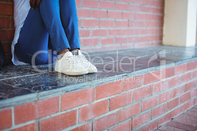 Schoolgirl sitting against brick wall