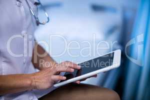 Mid section of female doctor using digital tablet