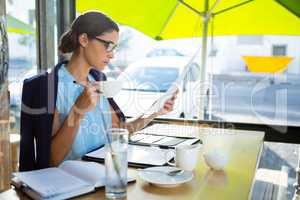 Female executive looking at document while having coffee