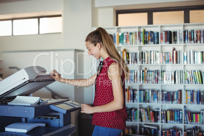 Happy schoolgirl using Xerox photocopier in library