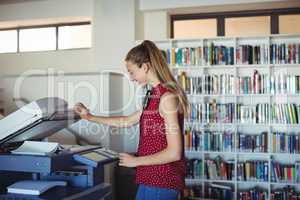 Happy schoolgirl using Xerox photocopier in library