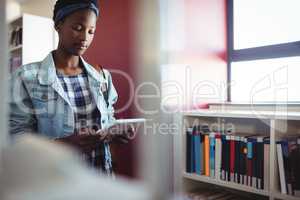 Attentive schoolgirl using digital tablet in library