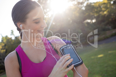 Smiling female jogger listening to music on mobile phone