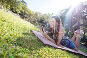 Smiling woman lying on mat and using digital tablet