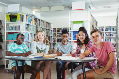 Portrait of happy classmates studying in library