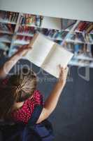 High angle view of attentive schoolgirl reading book in library
