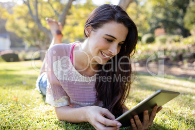 Woman lying on grass and using digital tablet