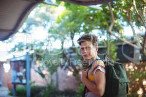 Happy schoolboy standing in school campus