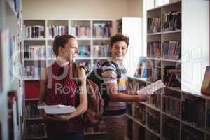 Classmates interacting while selecting book in library