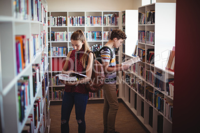 Attentive classmates reading book in library