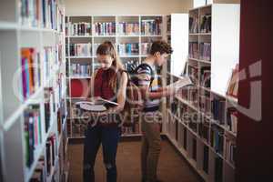 Attentive classmates reading book in library