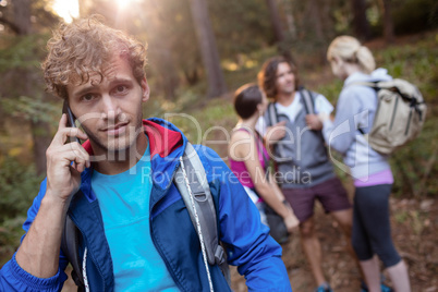 Young man talking on the phone while hiking with his friends